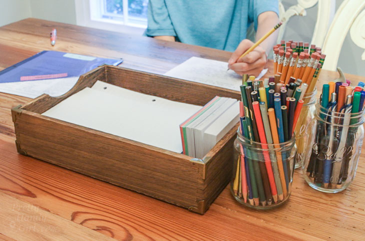 boy doing homework at table with school supplies in foreground