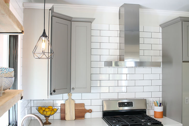 Subway tile backsplash, gray shaker cabinets, stainless steel range hood from Broan