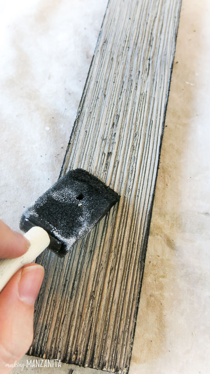 foam dry brushing black onto wood siding