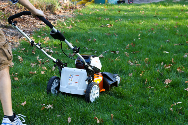 man pushing lawnmower shown from back